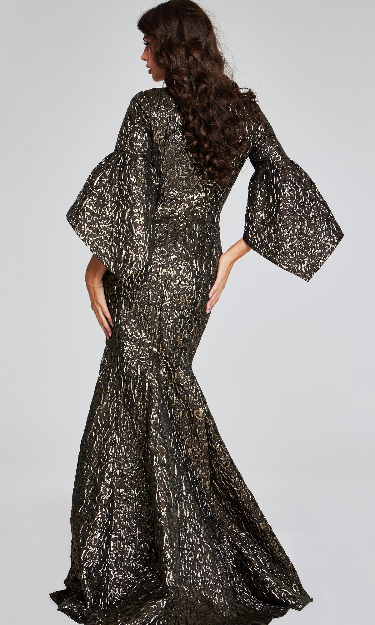 Woman wearing the Jovani 39080 long formal dress with a metallic pattern and wide sleeves, standing with her back to the camera against a plain background.